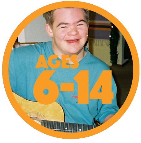 Teenage boy with Down syndrome in blue shirt, smiling, playing guitar.