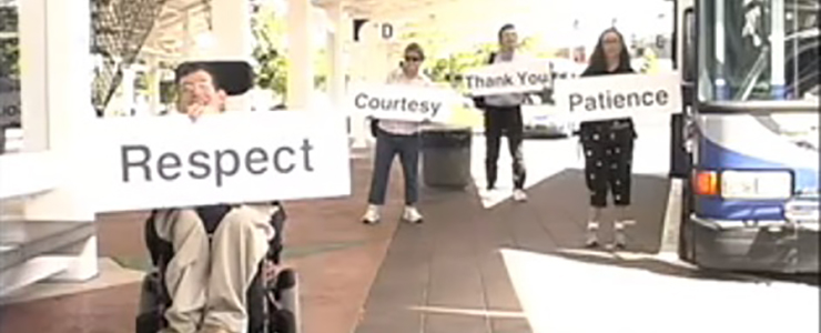 People with disabilities at transit center, holding signs that say Respect, Courtesy, Thank You, Patience