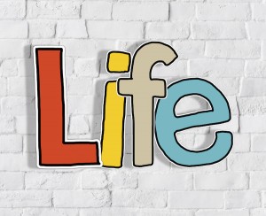 Multicolored text with the word Life set against a brick wall 