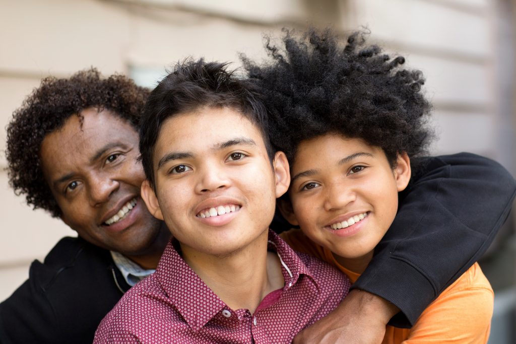 Portrait of an African American father hugging his sons.