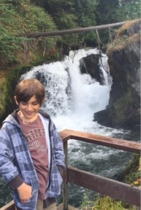 boy smiling, waterfall background