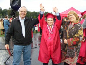 Silas in cap and gown, celebrating with his parents