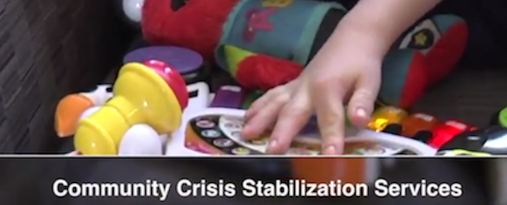 close up of a child's hand playing with brightly colored toys. Title over the image reads: Community Crisis Stabilization Services