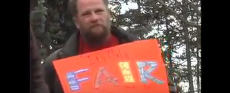 Kenny Miller holding a sign that reads FAIR: Freedom, Access, Independence, Respect