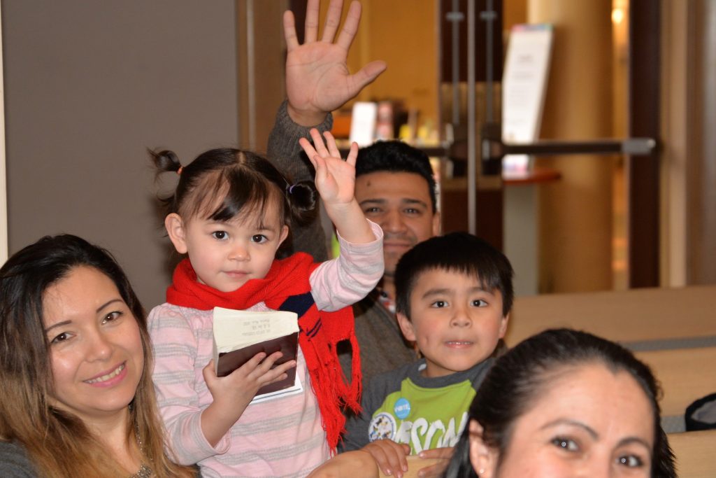 Family with small children, waving at the camera.