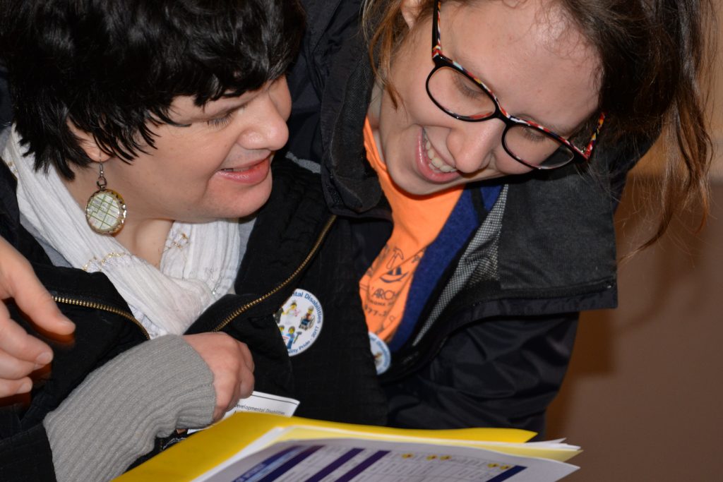 Close up picture of a woman with disabilities reading through materials with a support person.