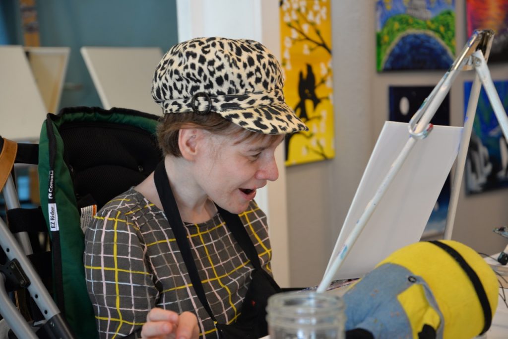 Woman, smiling, in art studio, painting.