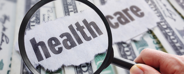 Magnifying glass looking at health care newspaper headline, on cash