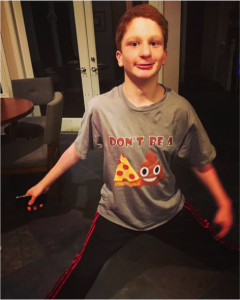 Teenager Nate mugging for the camera, wearing a t-shirt with the image of a pizza slice and poop emoji.