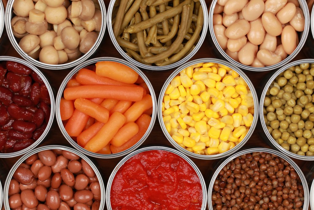 Different kinds of vegetables such as corn, peas and tomatoes in cans.