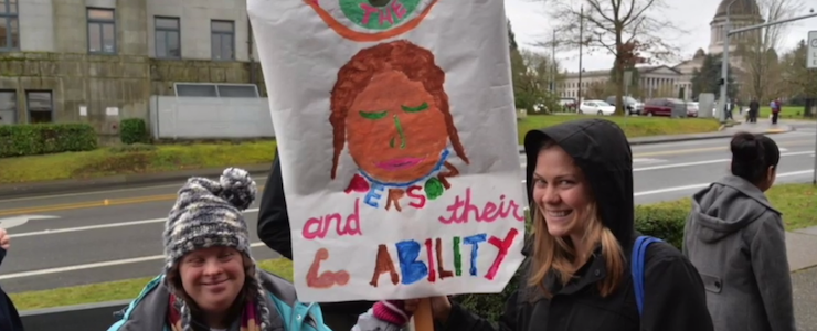 Disability advocates hold a sign that reads See the person and their ability.