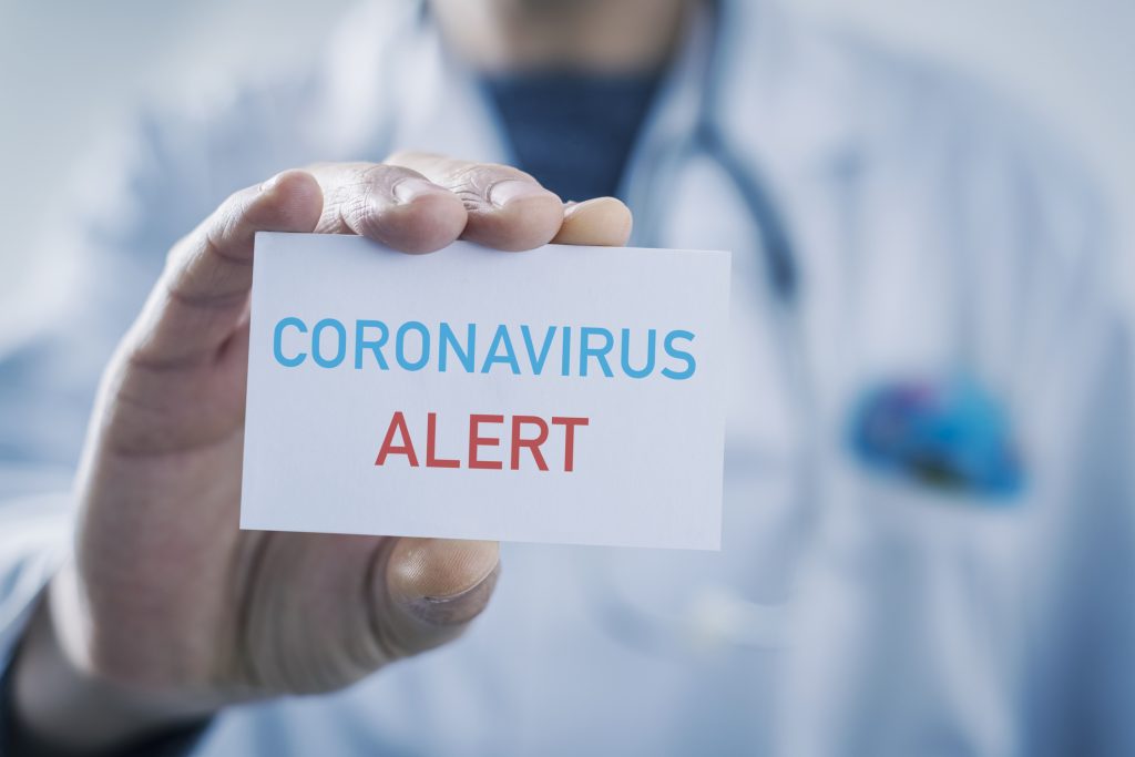 Closeup of a caucasian doctor man showing a sign with the text coronavirus alert written in it.