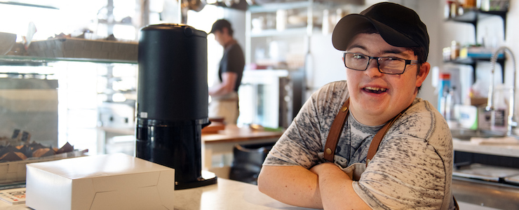 A man with Down syndrome working at the counter of a coffee shop.