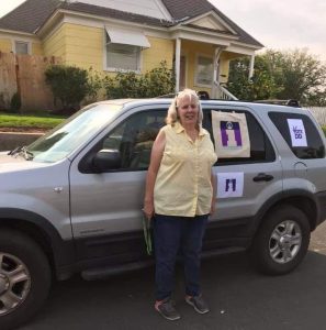 Debbie Chapman stands beside her car with Informing Families logos outside a car parade in Ritzville WA.