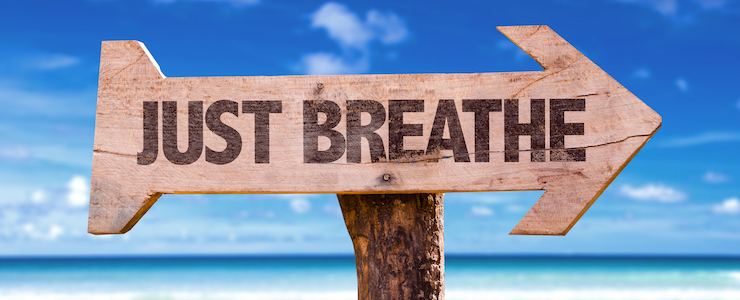 Just Breathe directional sign with a beach