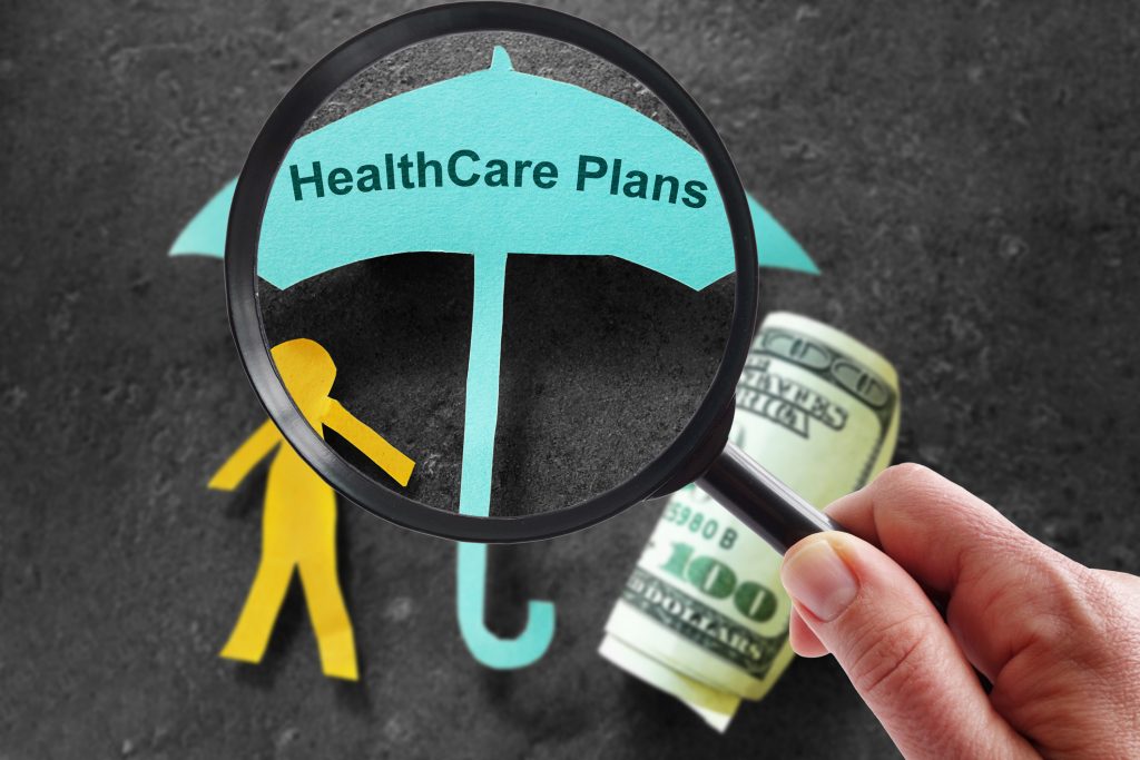 Person with magnifying glass and Healthcare Plans umbrella with cash