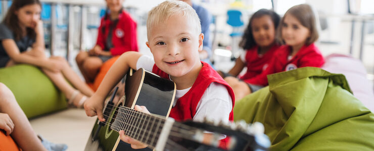 A boy with Down-syndrome playing guitar.
